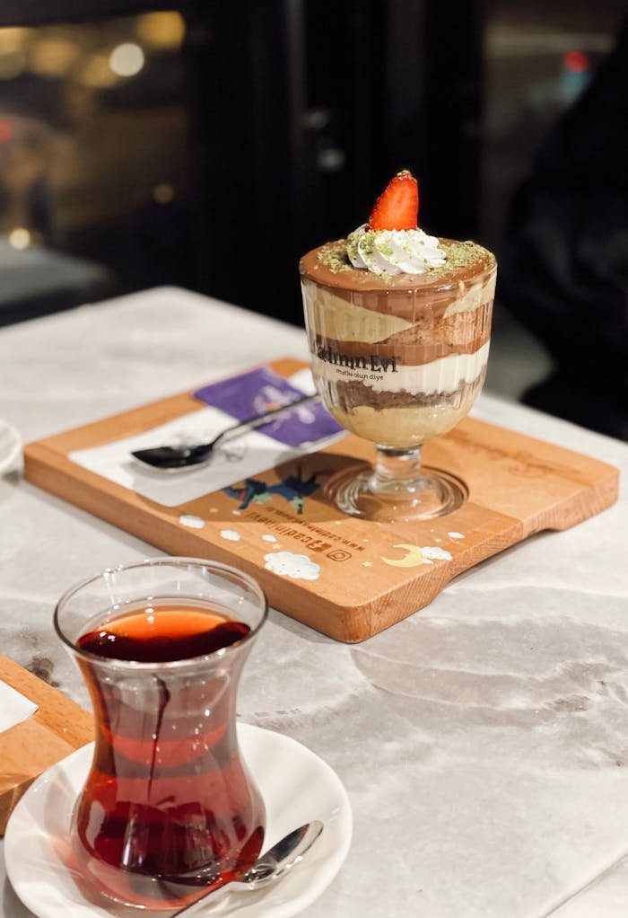 a-dessert-with-a-cup-of-tea-on-a-wooden-tray-28223896 Delicious layered dessert with a fresh strawberry, served with a glass of tea on a stylish board.